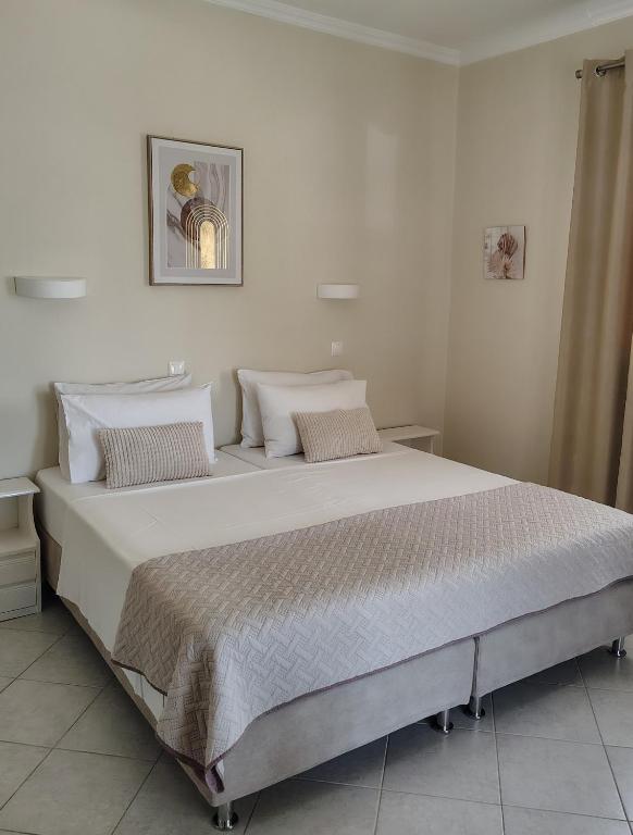 a large bed in a bedroom with white walls at Vicky's Guesthouse in Kavos