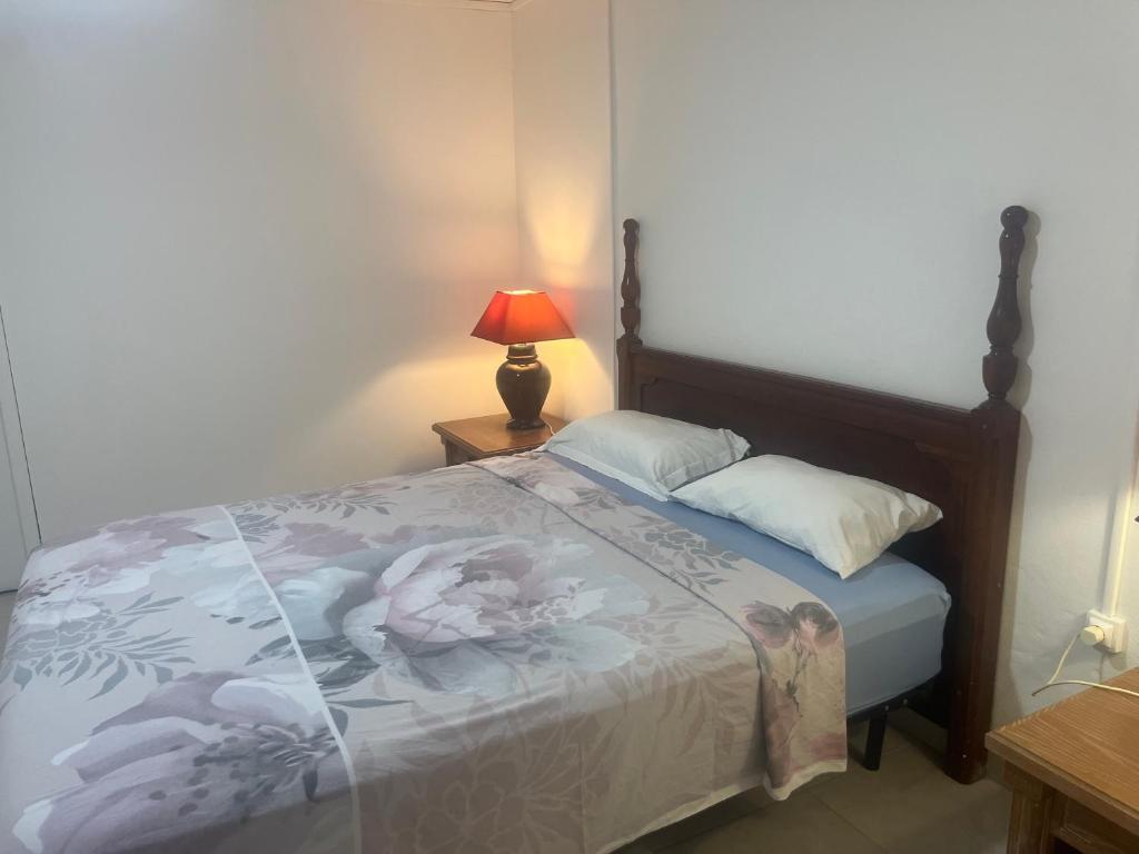 a bedroom with a bed and a lamp on a table at APPARTEMENT AMARYLLIS à 3 min de la PLAGE Pointe Marin in Sainte-Anne
