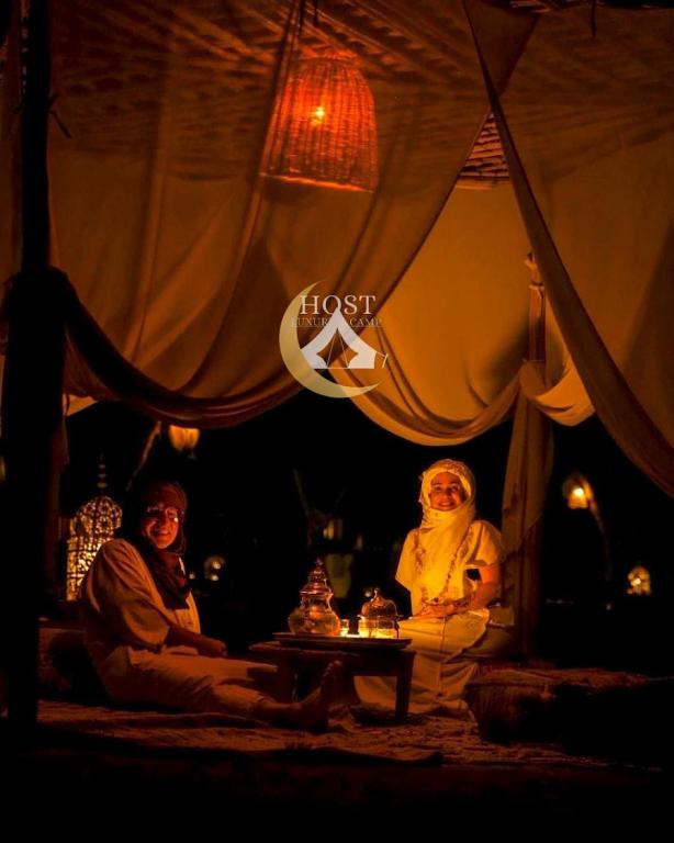 two people sitting in a tent at night at Host Luxury Camp in Merzouga