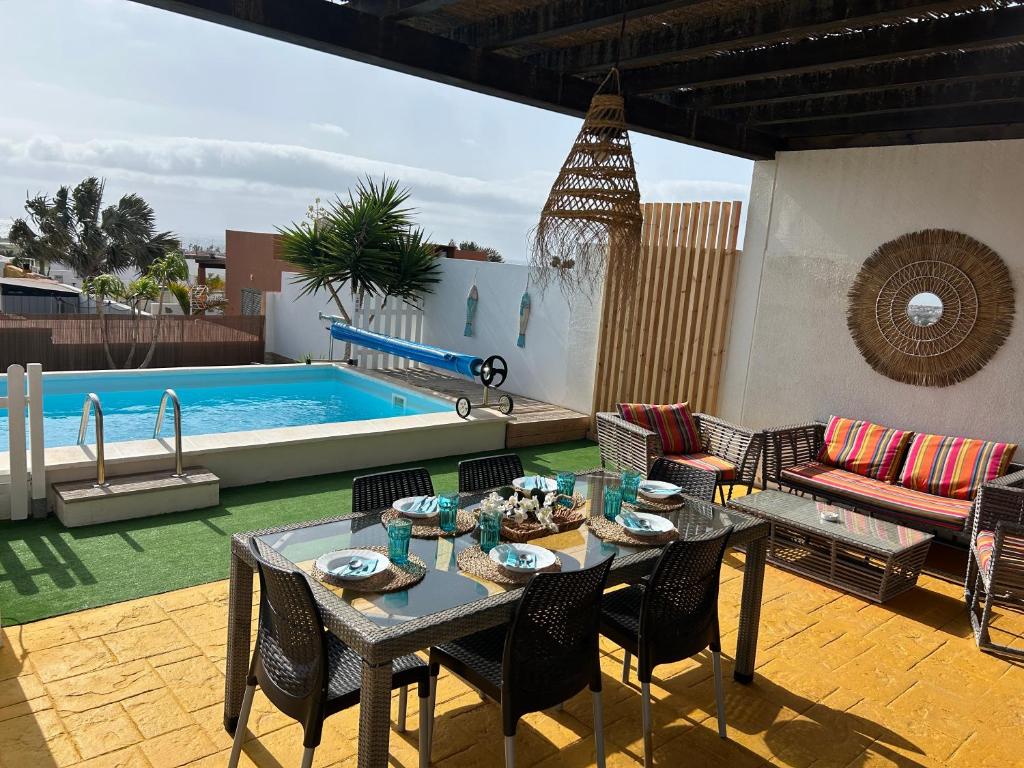 een terras met een tafel en stoelen en een zwembad bij Villa Dinateli, Salinas Golf in Caleta De Fuste