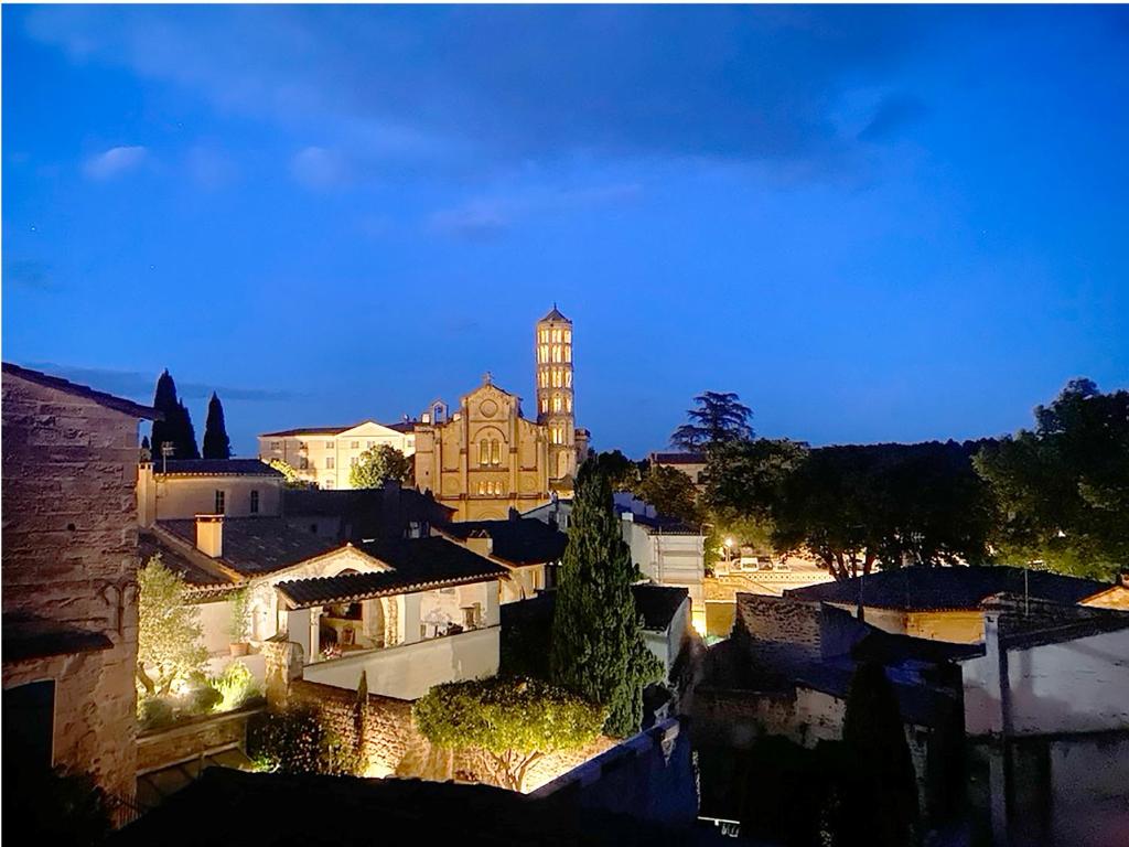 - une vue sur une ville la nuit avec une tour d'horloge dans l'établissement Chambre d'Hôte vue exepitonnelle, à Uzès