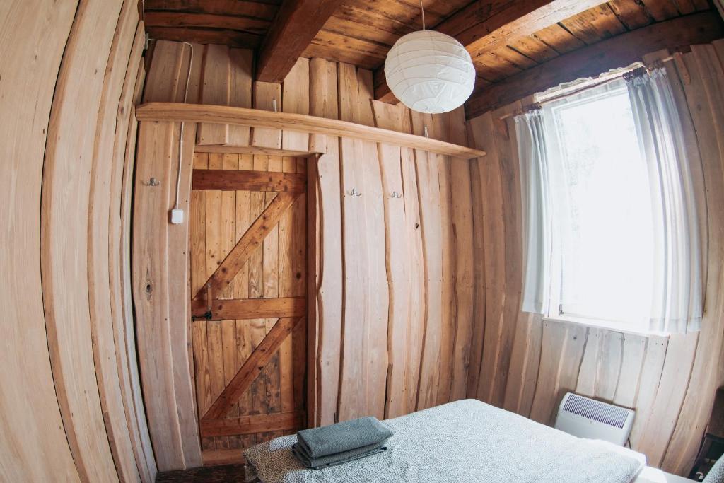 a bedroom with a wooden wall with a door at Sunny Nights Homestead Rustic House in Gataučiai