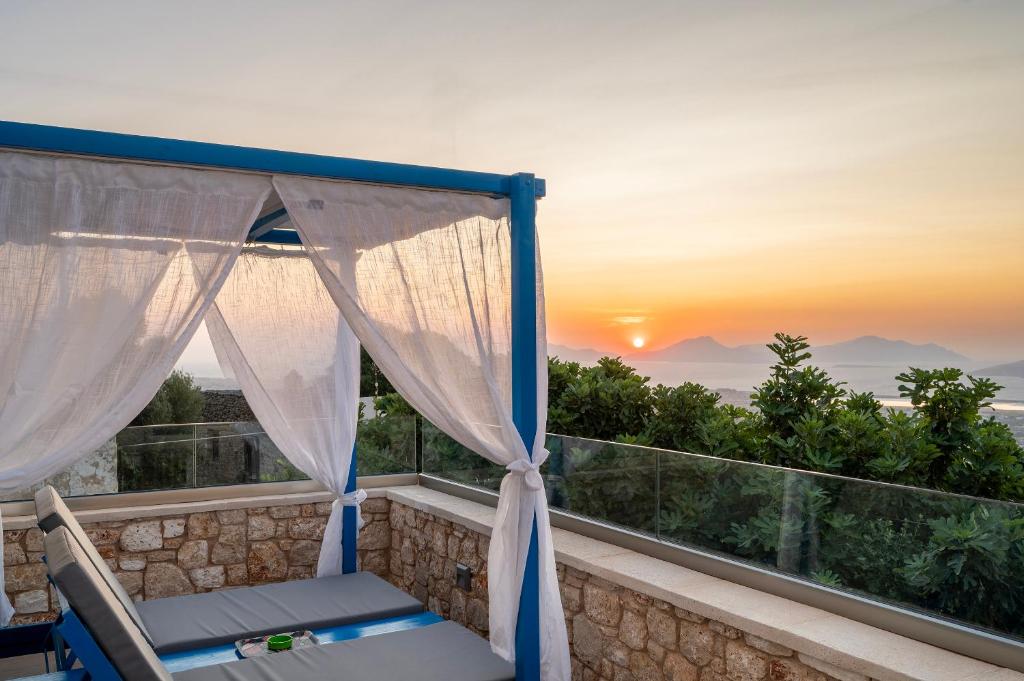 a balcony with a chair and a sunset at Archangel's Nest - Hug in Kos