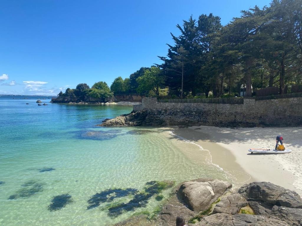 - une plage avec une personne dans un bateau dans l'eau dans l'établissement Plage des Dunes - Grand Studio ouvert avec 1 mezzanine et 1 alcôve, à Fouesnant