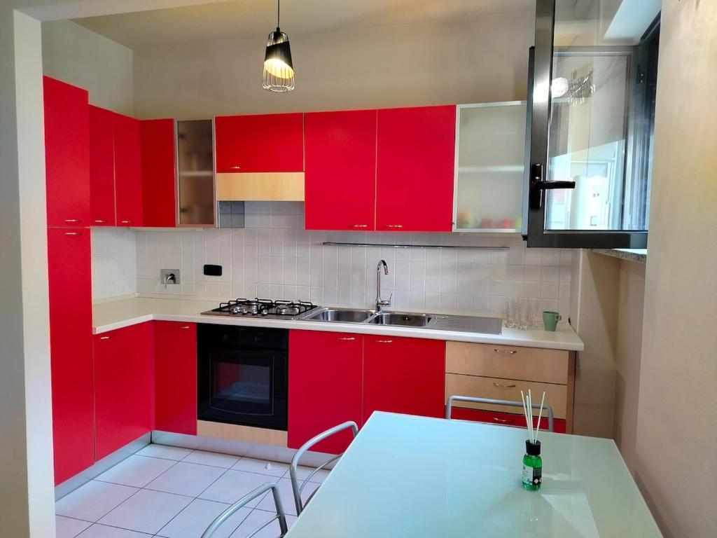 アルバにあるAlba Blu Apartmentのキッチン(赤いキャビネット、シンク、テーブル付)