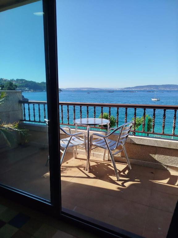 a table and chairs on a balcony with a view of the water at Maradentro in Bueu