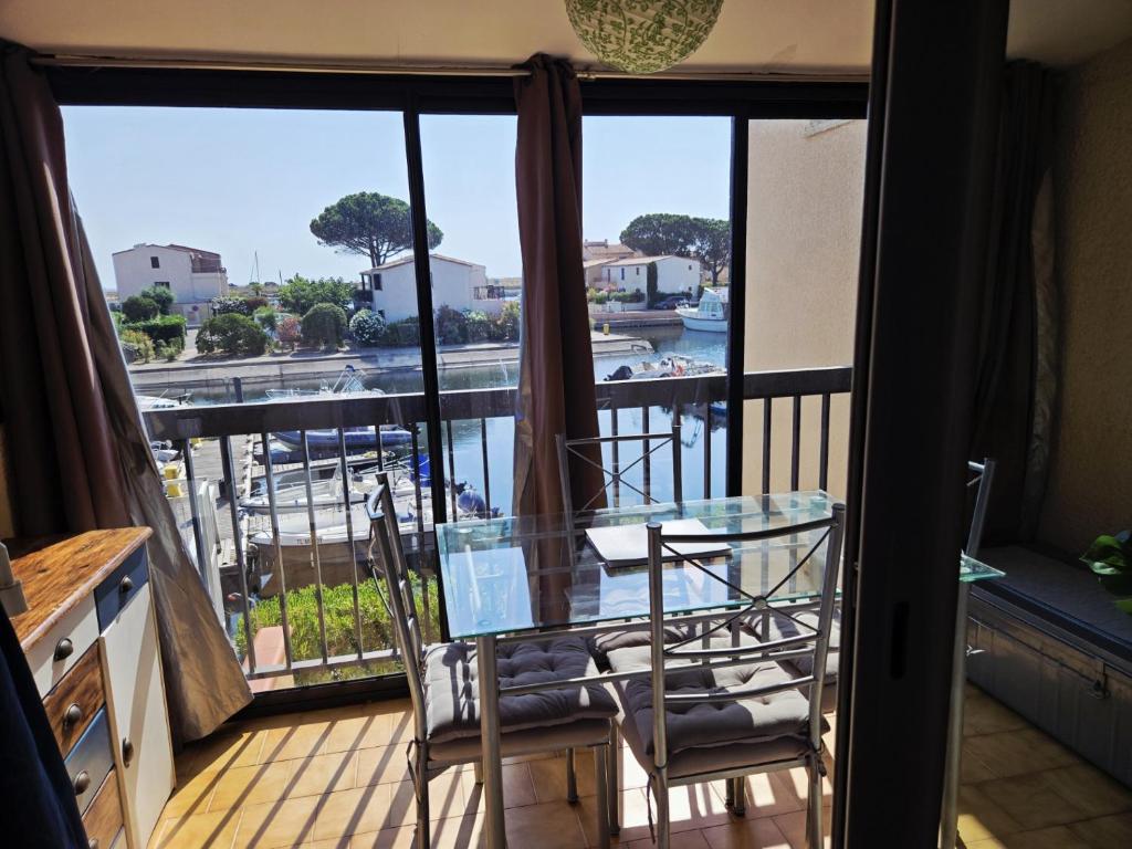 d'une table et de chaises en verre sur un balcon avec vue. dans l'établissement Appartement cosy avec vue sur la Marina - Résidence parking privé, à Saint-Cyprien