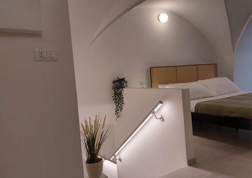 een slaapkamer met een bed en een trap met een plant bij VIALI Guest House in Fasano