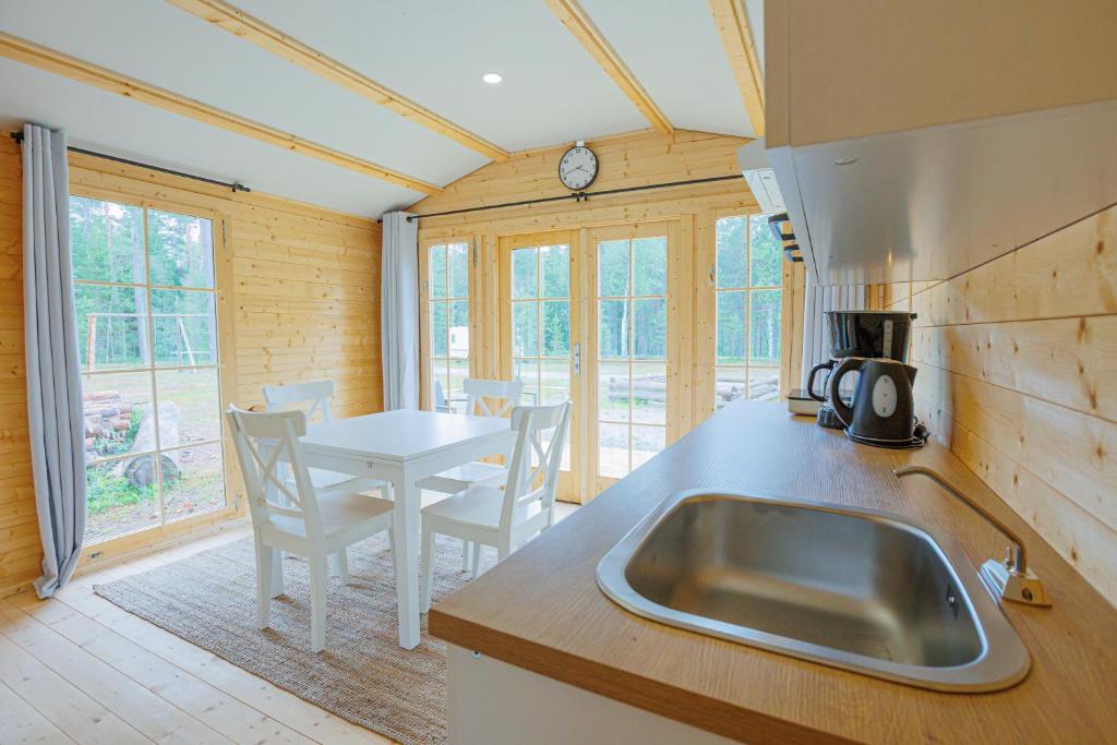 une cuisine avec un évier et une table avec des chaises dans l'établissement Gustava Parken - 3 persons cottage, à Hagfors