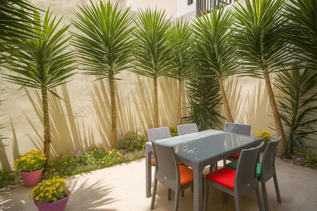 グジラにあるAzure Haven - Gzira Apartments and Penthouse By ShortLetsMaltaのヤシの木が茂る中庭(テーブル、椅子付)