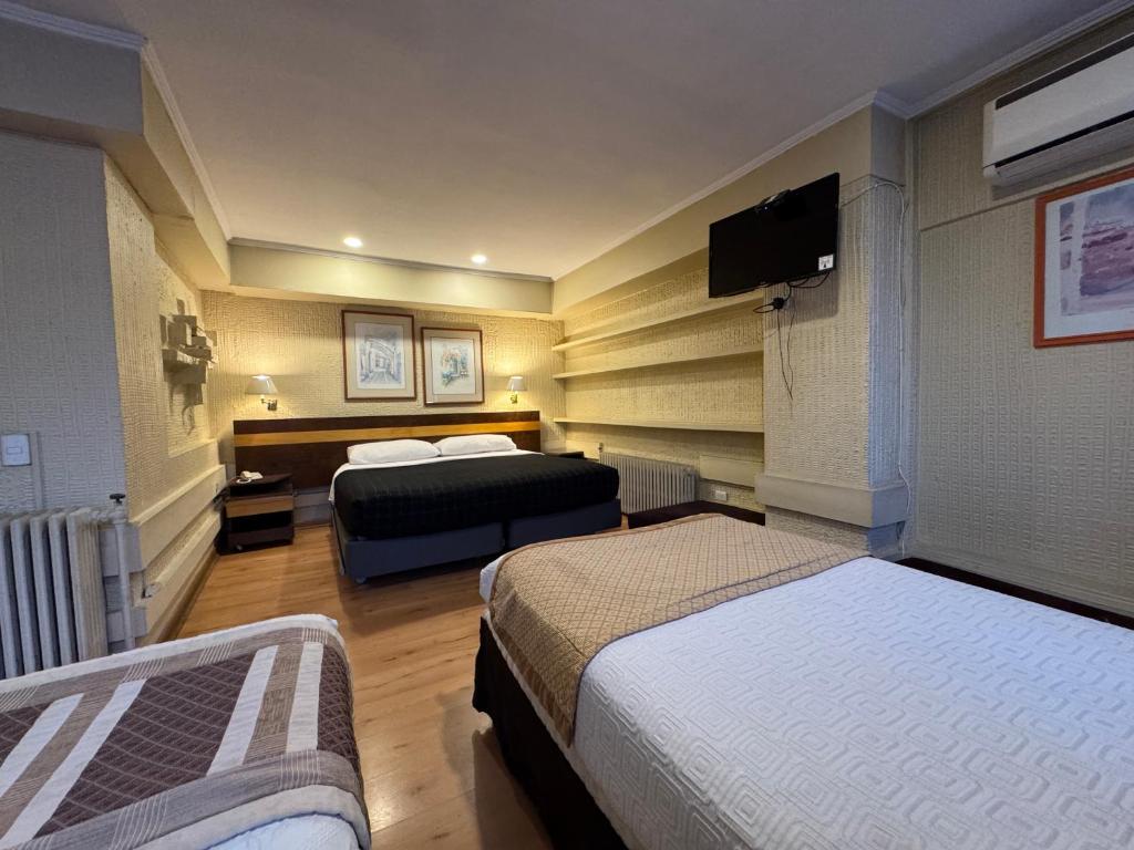 a hotel room with two beds and a flat screen tv at Intimo Hotel Miraflores in Santiago