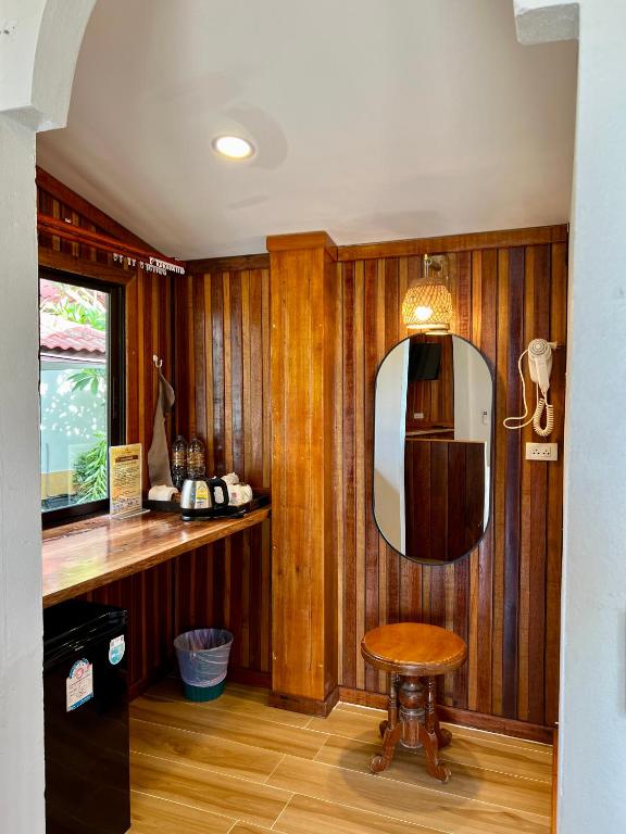 ein Raum mit Holzwänden und einem Spiegel und einem Hocker in der Unterkunft Pen's Bungalow Koh Phangan in Thong Nai Pan Yai