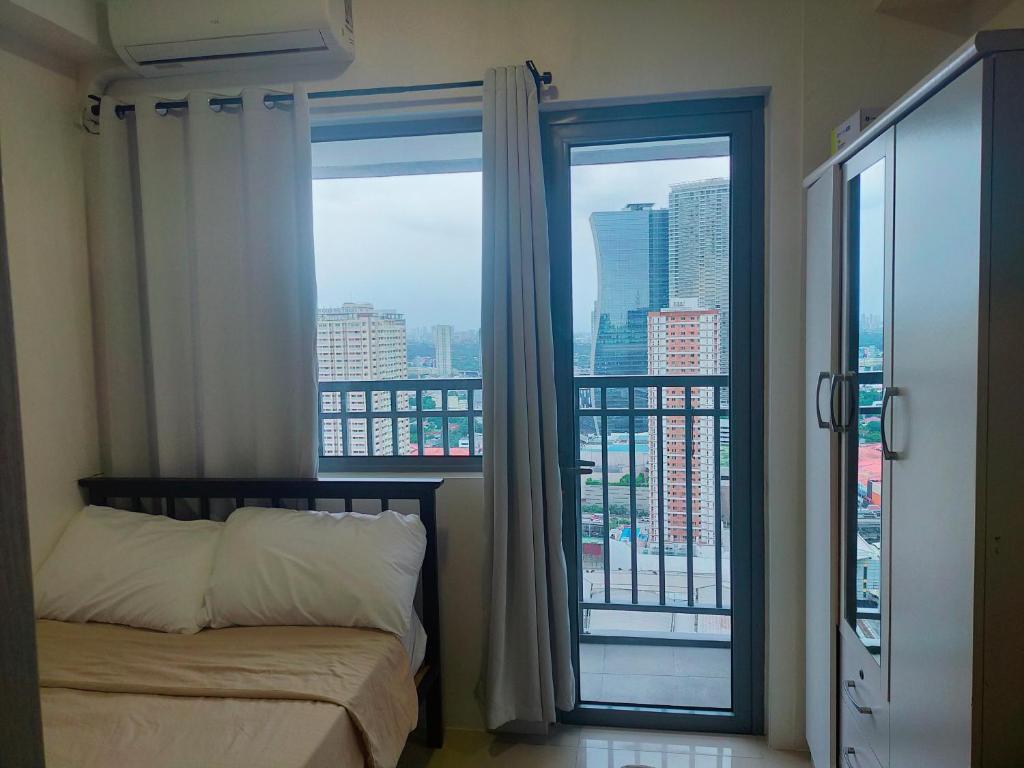 a bedroom with a bed and a large window at Fame Residences Tower 1 in Manila