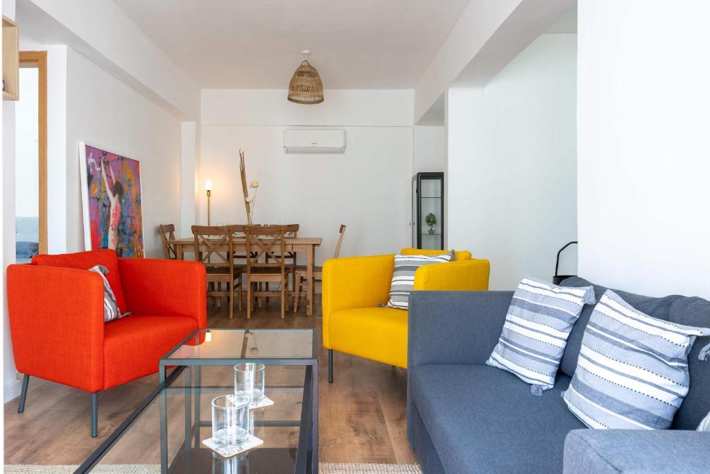 a living room with colorful chairs and a table at Stylish 2BR Apartment with Rooftop Pool in Mackenzie in Larnaca