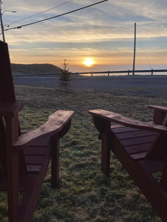 two wooden benches sitting in a field with the sunset at The Gateway Suite in Fortune