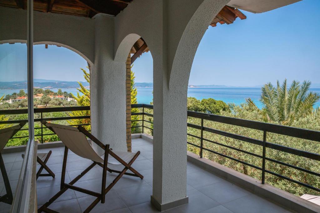 a room with a balcony with a chair and the ocean at Villa LaThea in Akti Salonikiou