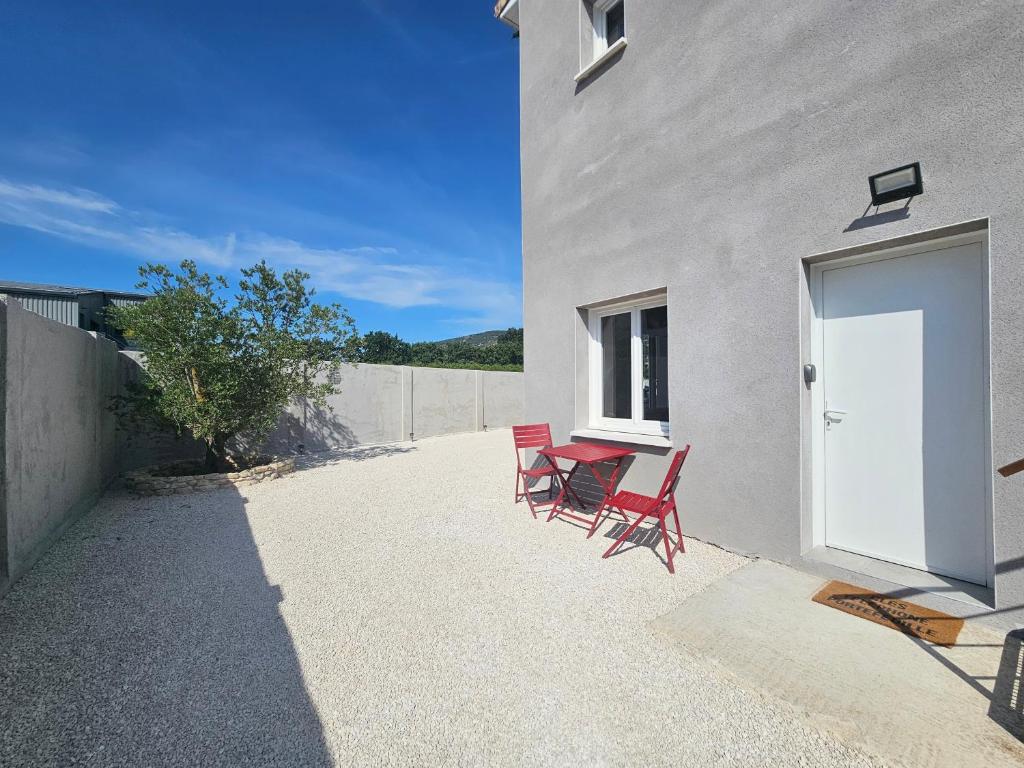two red chairs and a table next to a building at studio 2 personnes toutes équipées in Malataverne