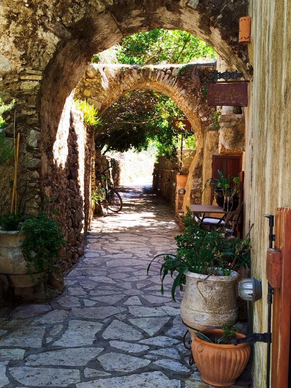 an archway with potted plants on a stone pathway at Porfyrousa Traditional Hotel in Milopótamos
