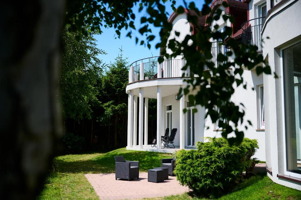 a white house with chairs in front of it at Villa Scolia in Niechorze