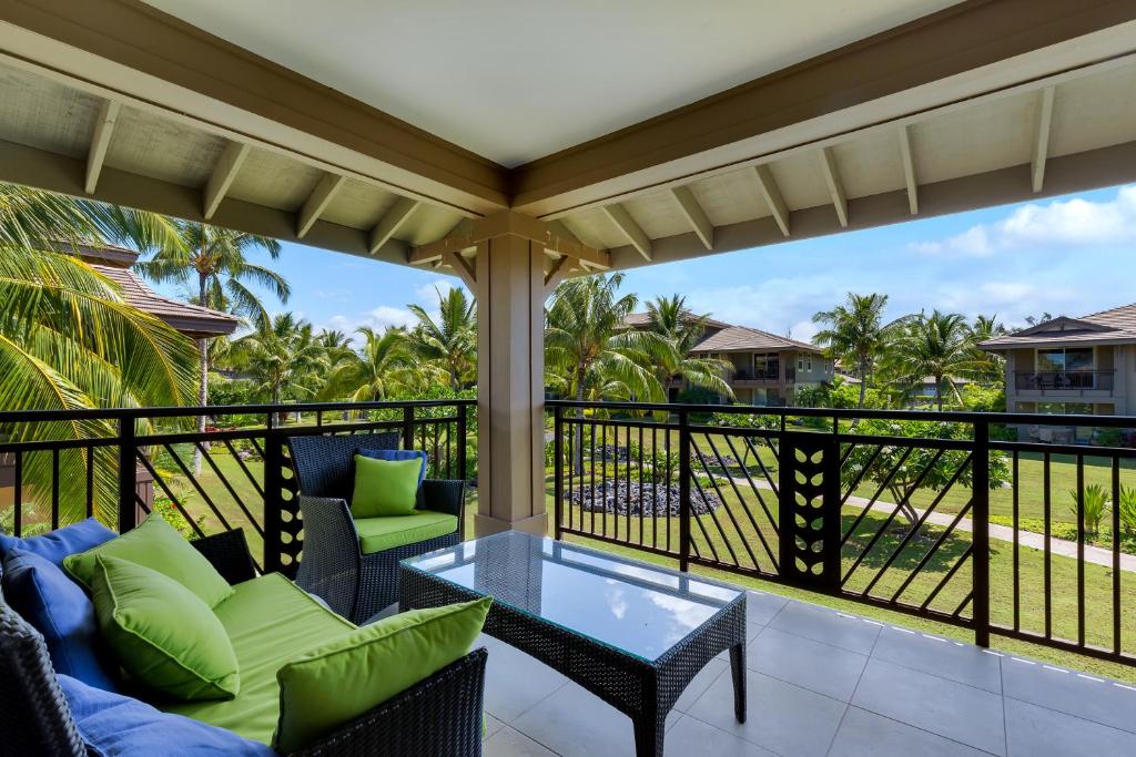 a porch with chairs and a glass table on a balcony at CASTLE Hali'i Kai at Waikoloa in Waikoloa