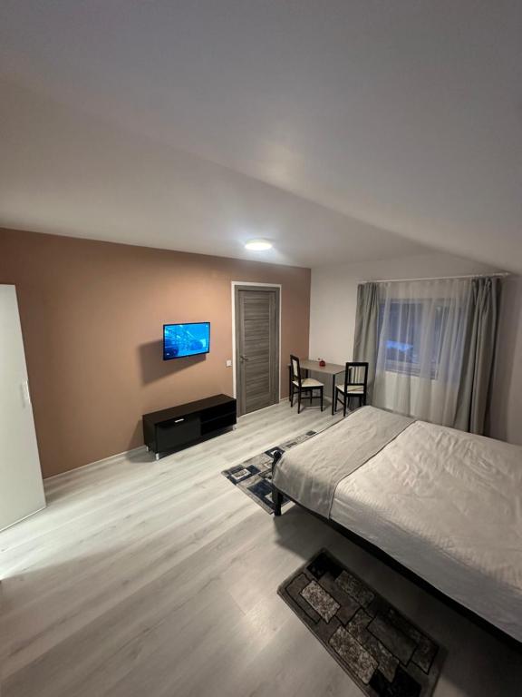 a bedroom with a bed and a table and a tv at Azuga Home in Azuga