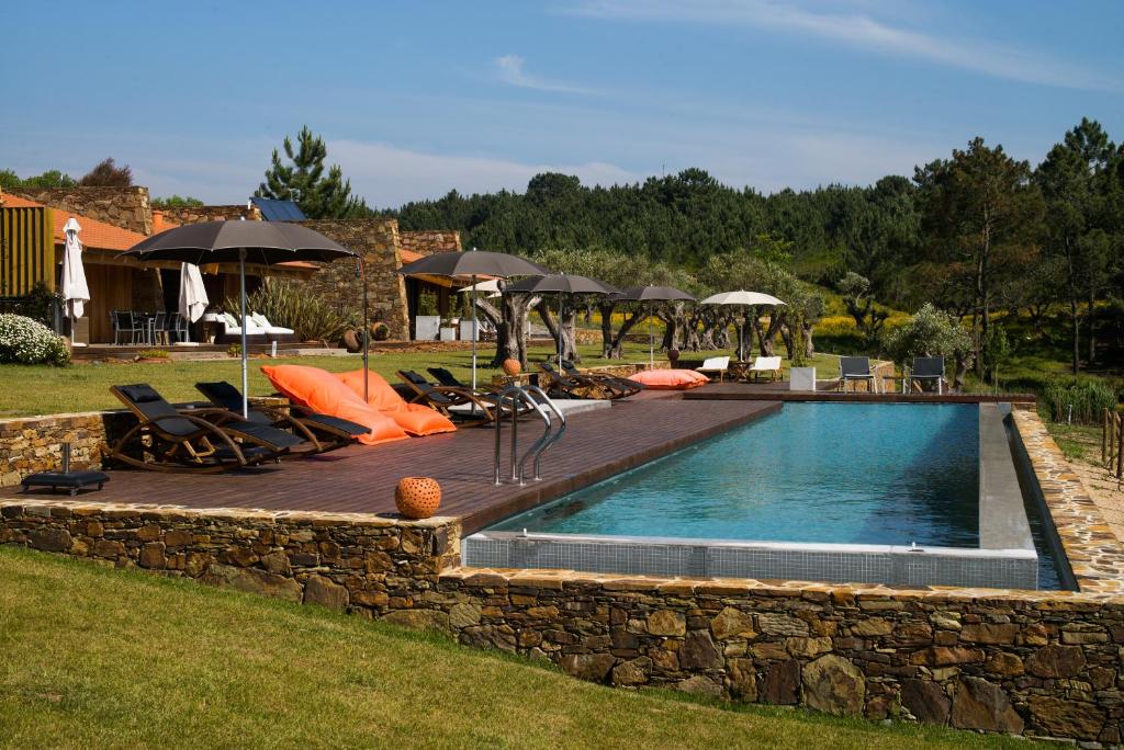 una piscina con sillas y sombrillas en un patio en TEIMA, Alentejo SW, en São Teotónio