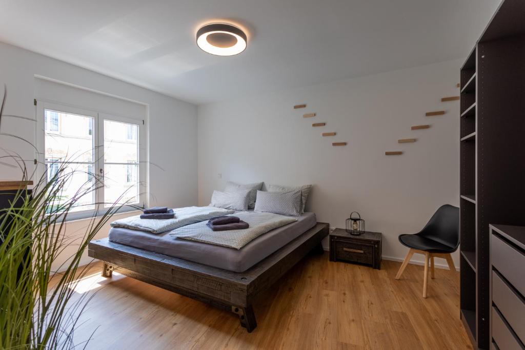 a white bedroom with a bed and a chair at C8 Loft - direkt in der Altstadt inkl Parkplatz in Überlingen