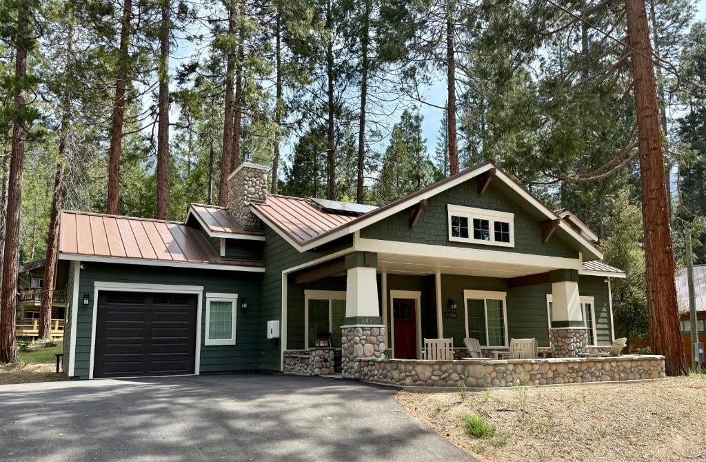 a green house with a garage in the woods at 56 Black Bear Bungalow in North Wawona