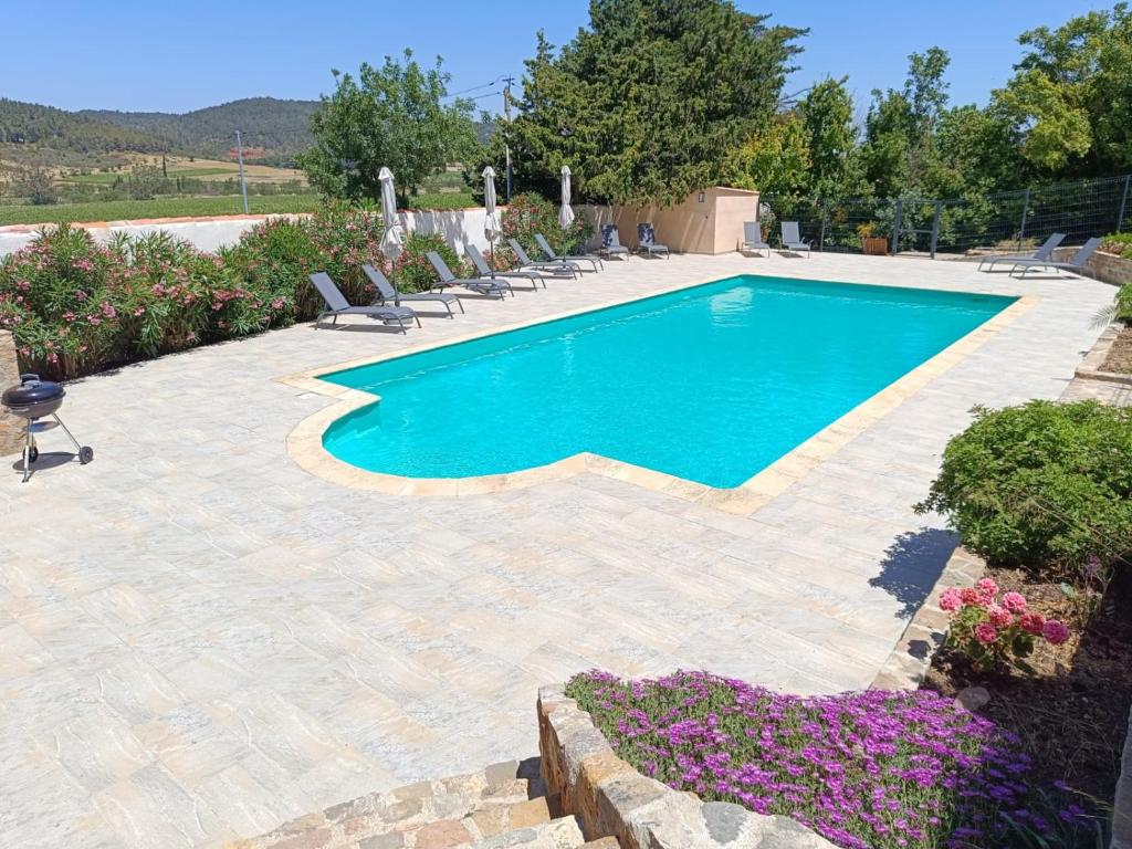 a swimming pool with chairs and flowers in a yard at Château de Prax Viel - piscine et mini ferme, climatisé in Lagrasse