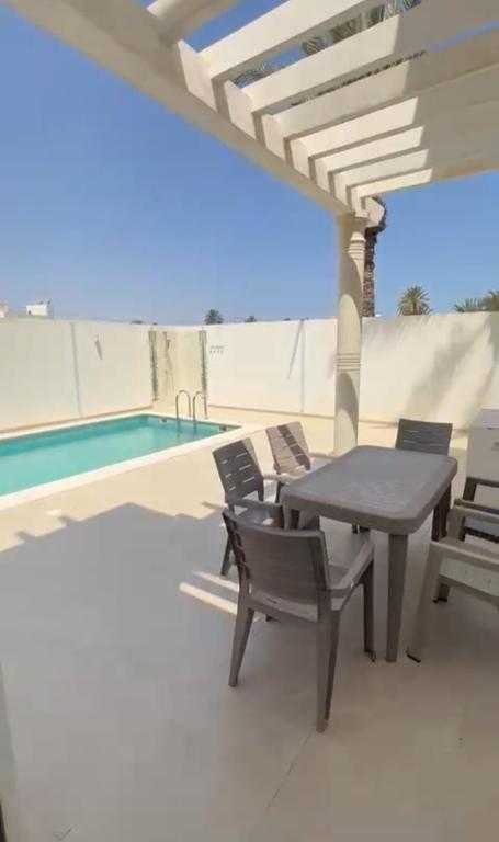 eine Terrasse mit Tisch und Stühlen neben einem Swimmingpool in der Unterkunft Dar Aïcha in Triffa