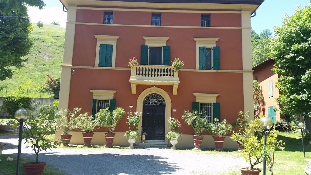 Casa grande de color naranja con balcón en la parte delantera en B&B Villa Storica Calderino, en Monte San Pietro