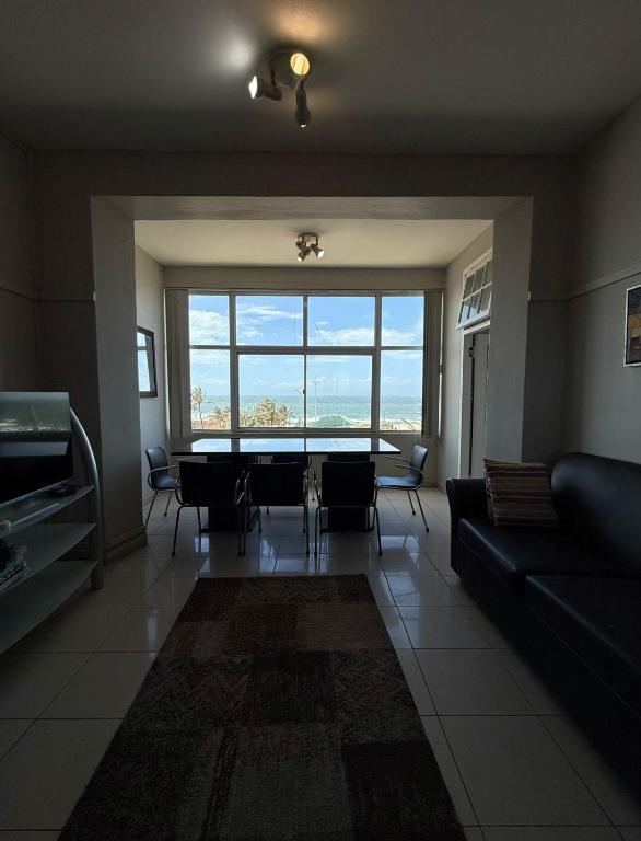 ein Wohnzimmer mit Tisch und großem Fenster in der Unterkunft Durban Beach flats Marine Parade in Durban