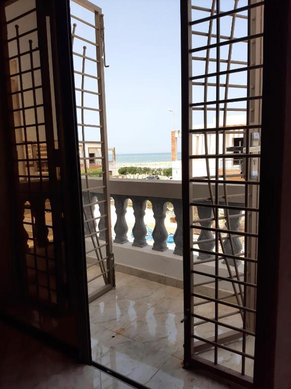 an open door to a balcony with a view of the ocean at Beach Front Villa in Souira Guedima