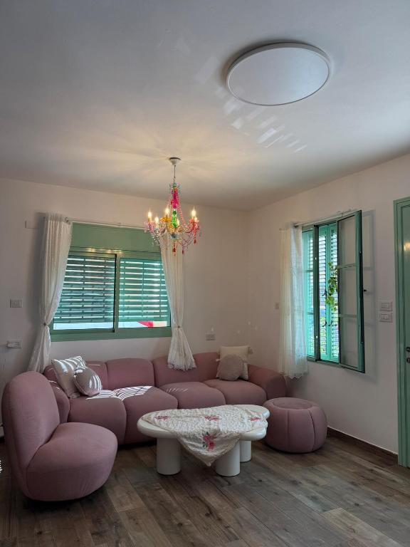 a living room with a pink couch and a chandelier at Matilda's house in Majdal Shams