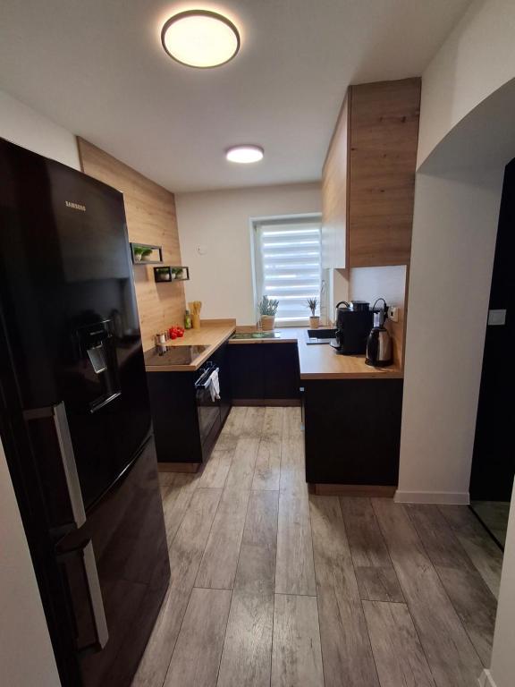 a kitchen with a refrigerator and wooden floors at Palmiarnia Point blisko Książ in Wałbrzych
