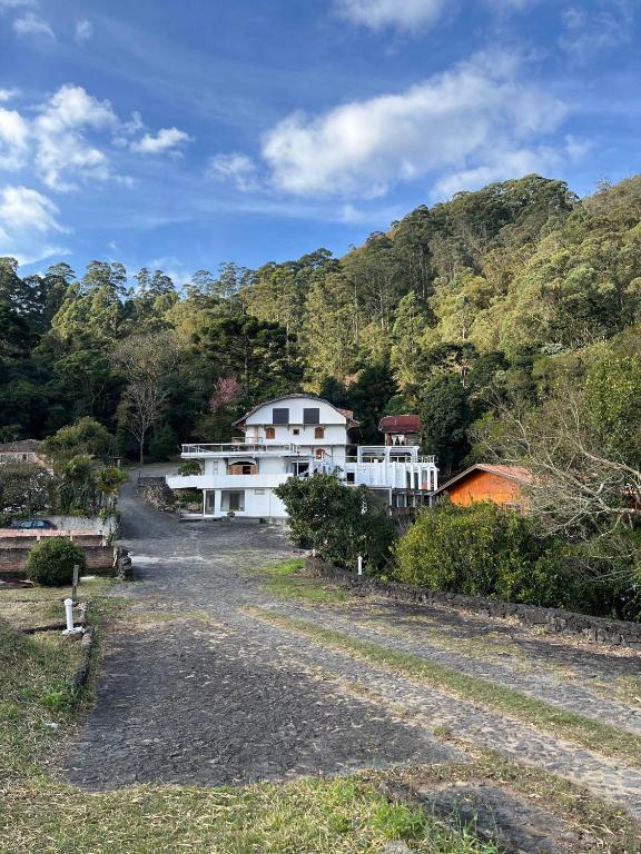 a white house in the middle of a dirt road at Pousada Saint Claire in Santo Antônio do Pinhal