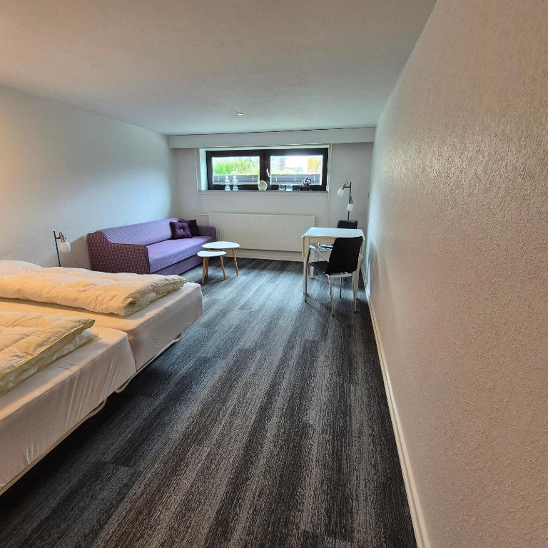 a bedroom with a bed and a couch and a table at Studiolejlighed I Hvide Sande Centrum in Hvide Sande