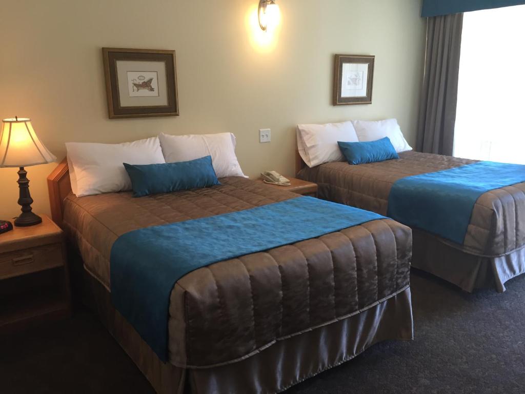 a hotel room with two beds with blue sheets at Motel Du Chevalier in Gatineau