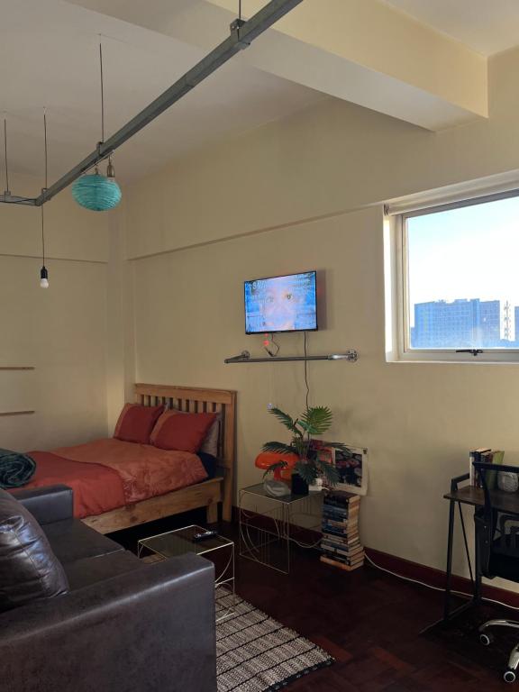 a bedroom with a bed and a couch and a window at I Know a Spot! In Johannesburg in Johannesburg