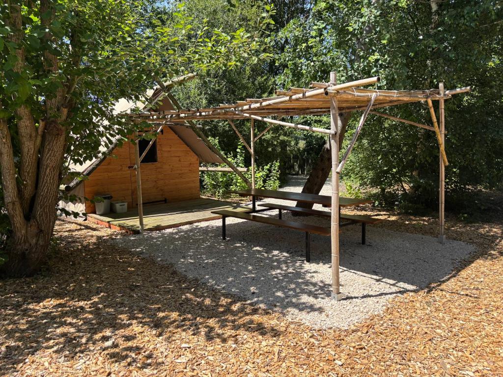une pergola en bois avec une table de pique-nique en face d'une cabane dans l'établissement Camp du Père Castor, à Simard