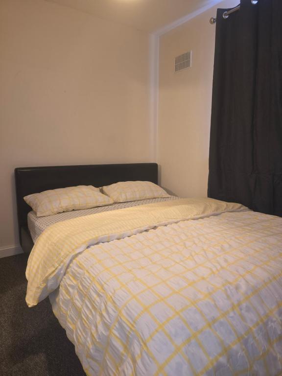 a bed with a yellow and white comforter in a bedroom at Cozy room in Wolverhampton city centre in Wolverhampton