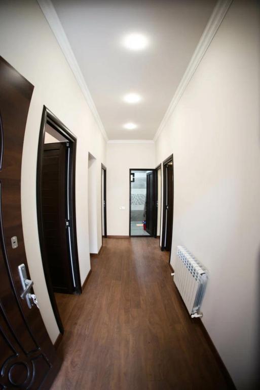 a hallway with white walls and wooden floors and a door at Maison spacieuse à Erevan in Aghk'ilisa