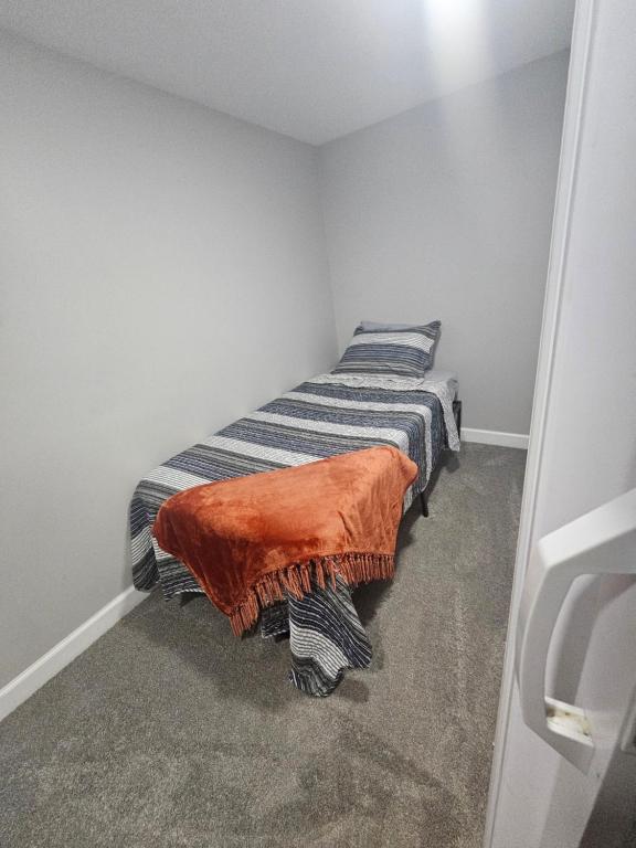 a small bedroom with a bed with an orange blanket at Welcome in Woodlawn