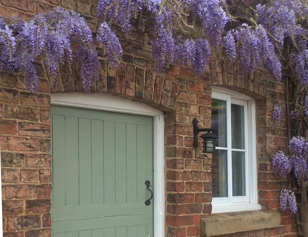 a house with purple wisterias over the door at The Stables at Owlett Hall in Crowle