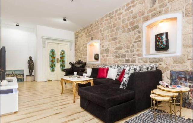 uma sala de estar com um sofá preto e uma parede de pedra em Apartment Papalić Palace em Split