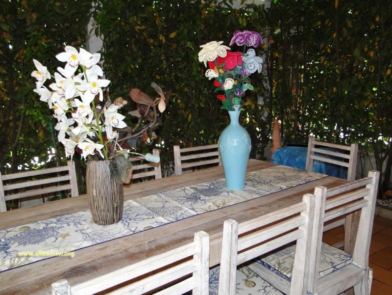 a wooden table with a blue vase with flowers on it at Villetta Marina in Roseto degli Abruzzi