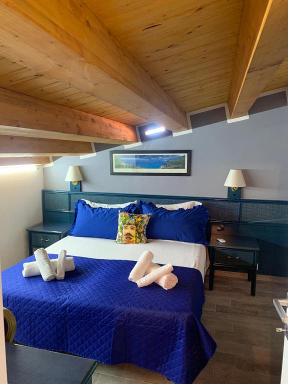 a bedroom with a large bed with blue sheets and slippers at U muragliuni 1 in Lascari