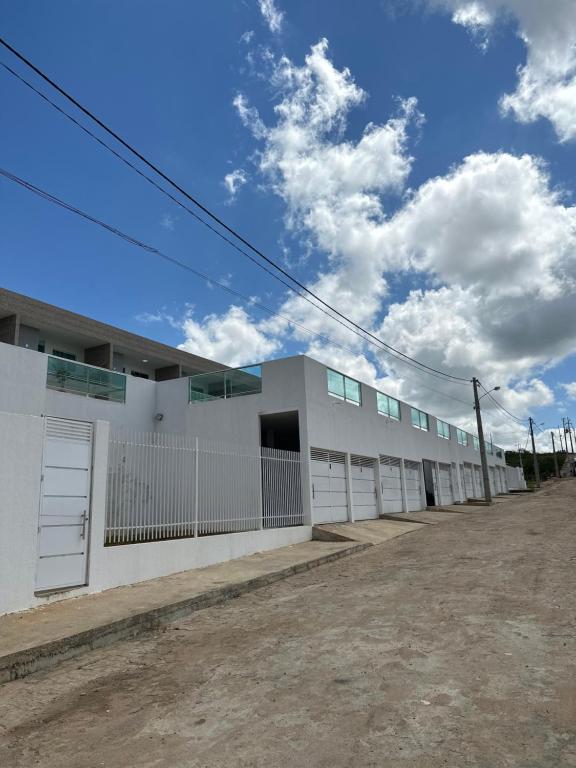 a row of white buildings on a dirt road at Condominio HOME DUPLEX SERRA NEGRA in Bezerros