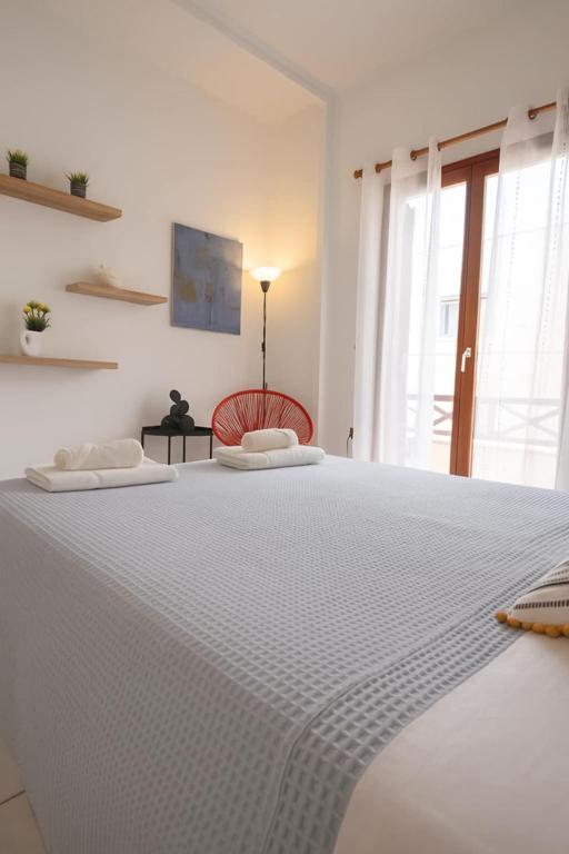 a bedroom with a large white bed with a red chair at Rodi Apartment 2 in Kamari