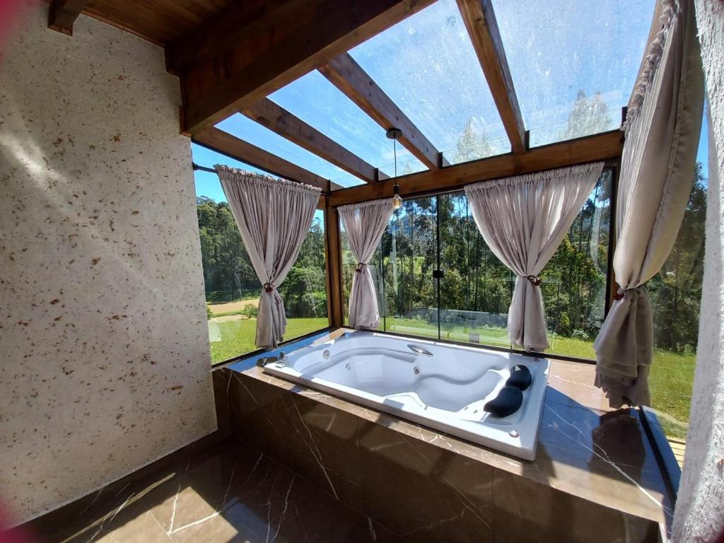 a jacuzzi tub in a room with windows at Chalés Sol da Serra - Eucalipto in Rio Rufino
